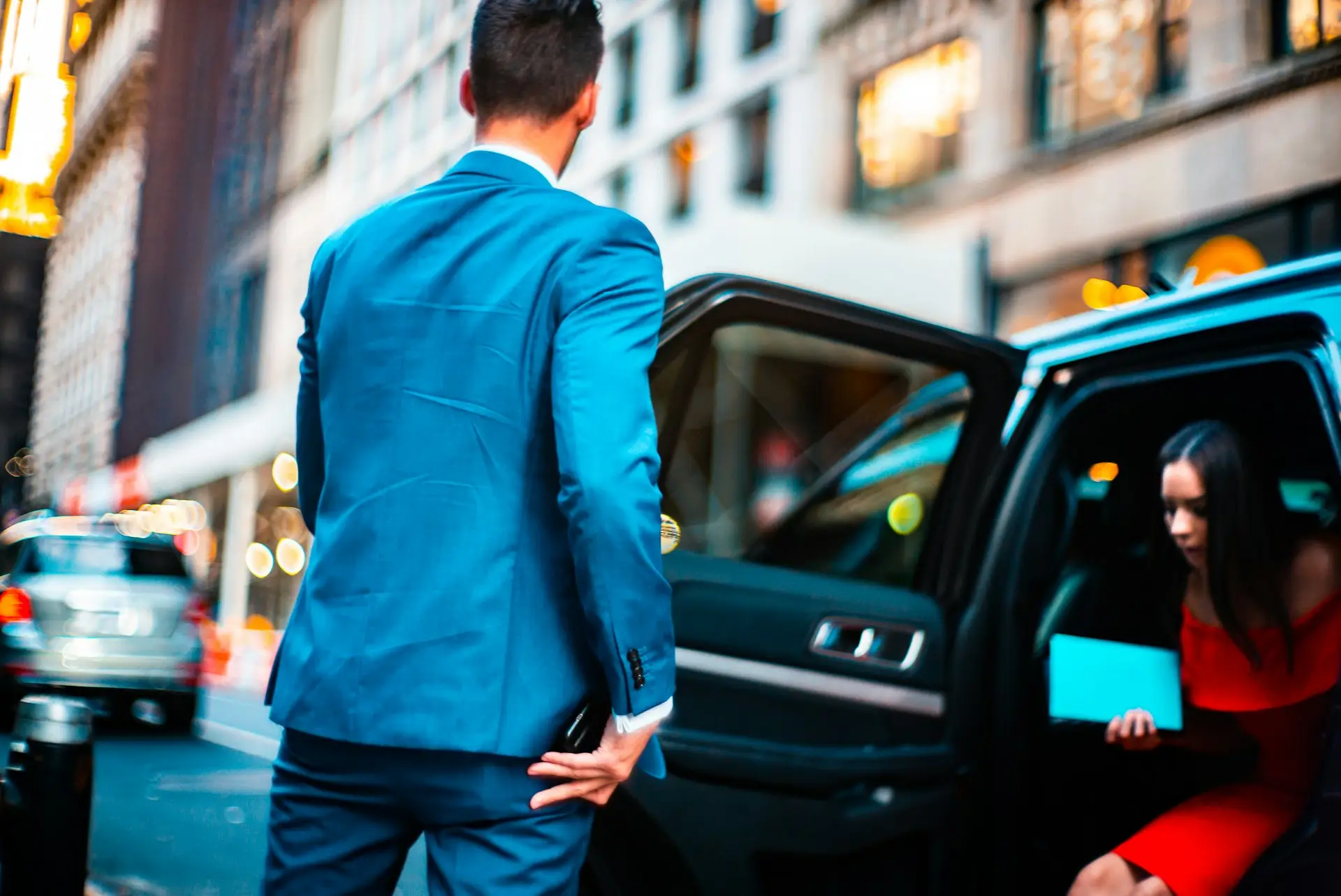 Chauffeur en costume ouvrant la portière à une cliente
